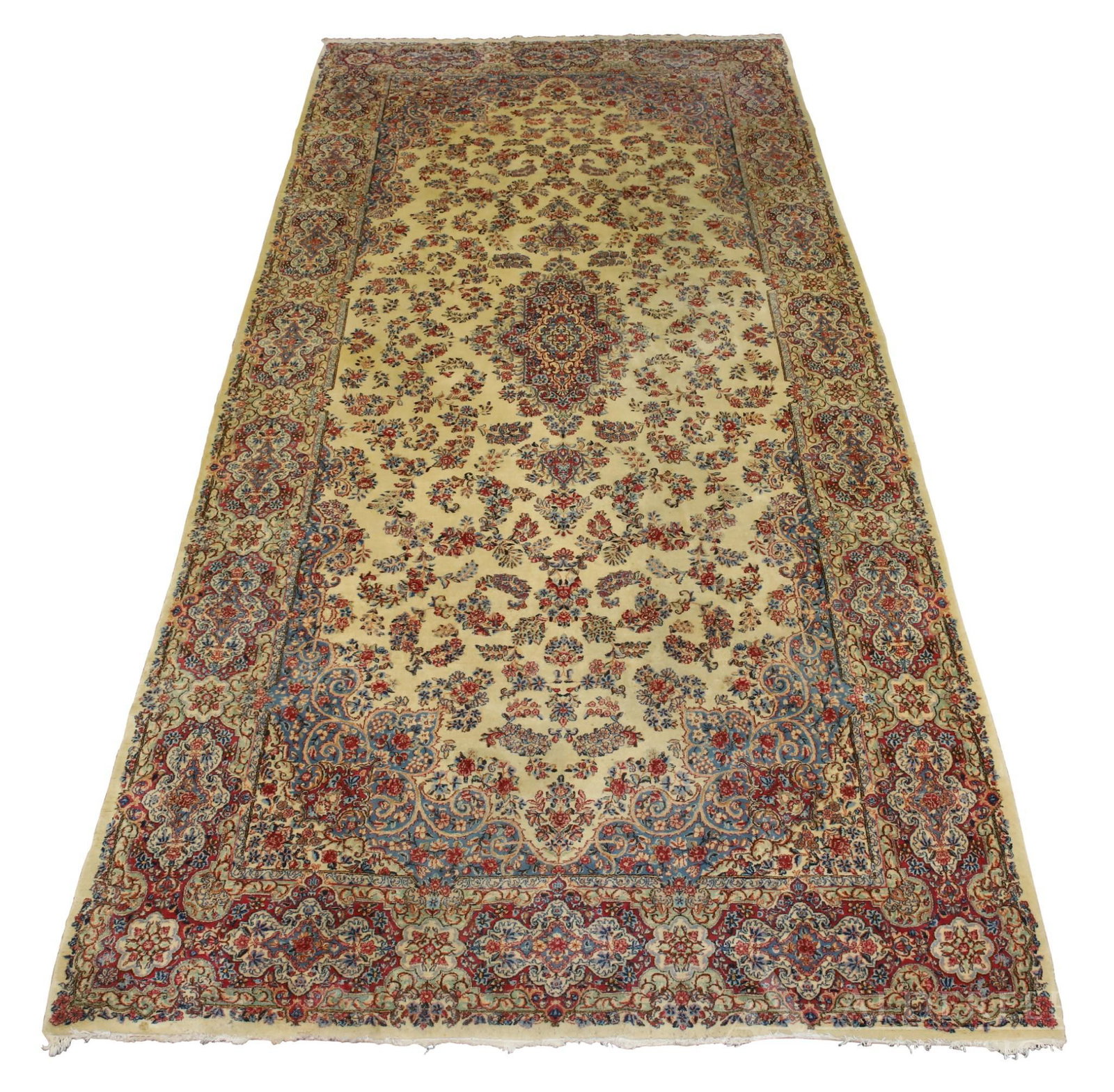 Kerman Palace Carpet: Oblong diamond floral medallion in a cream field with blue floral and sprig spandrels and a repeating floral main border. 1" moth damage along one end and fringe area of the rug. 19'8" l x 9'8"w