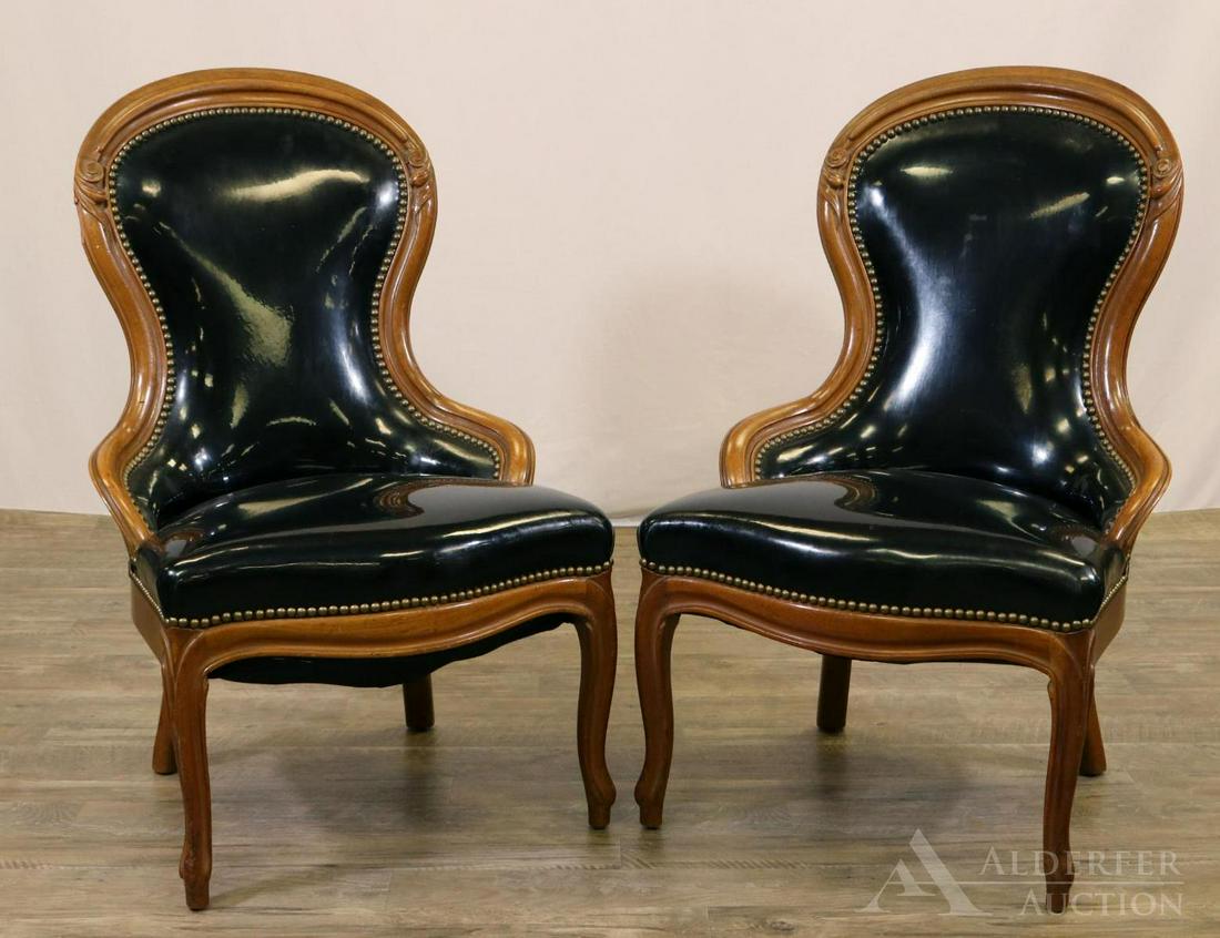 Pair of Victorian Slipper Chairs: Chairs with curved back and decorative scroll carving. Upholstered in black vinyl and decorative brass tacking along back and seat. 37"h x 22"w x 18"d