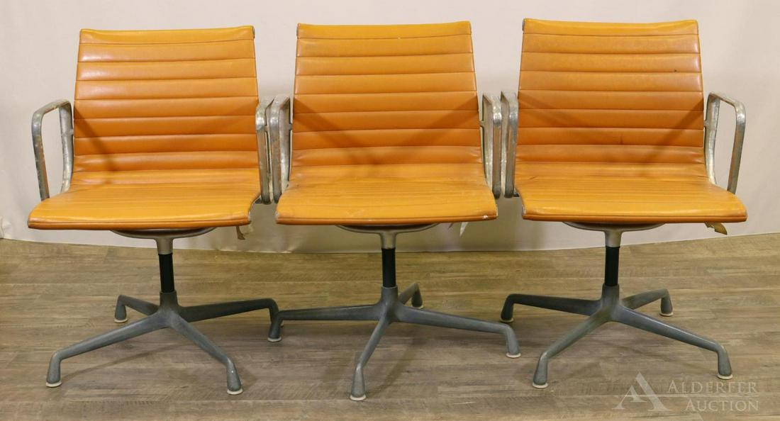 Charles Eames for Herman Miller Armchairs: Aluminum and orange vinyl swivel armchairs (3). 34"h x 23"w x 22"d