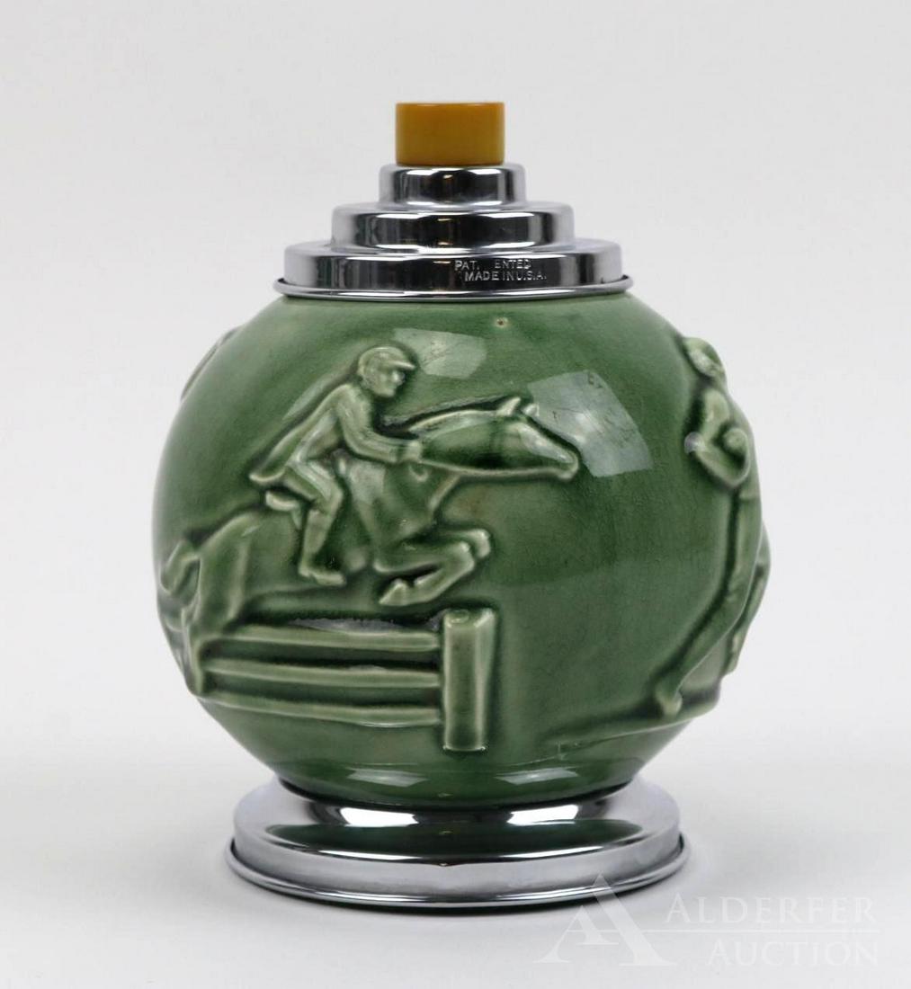 Cigarette Dispenser Attributed to Rookwood Pottery: Art deco ceramic cigarette dispenser with chrome and Bakelite accents. Green glazed body with athletes in relief form. Lid pulls up to fan out/dispense cigarettes. Marked on top "Pat. Ented Made In U.