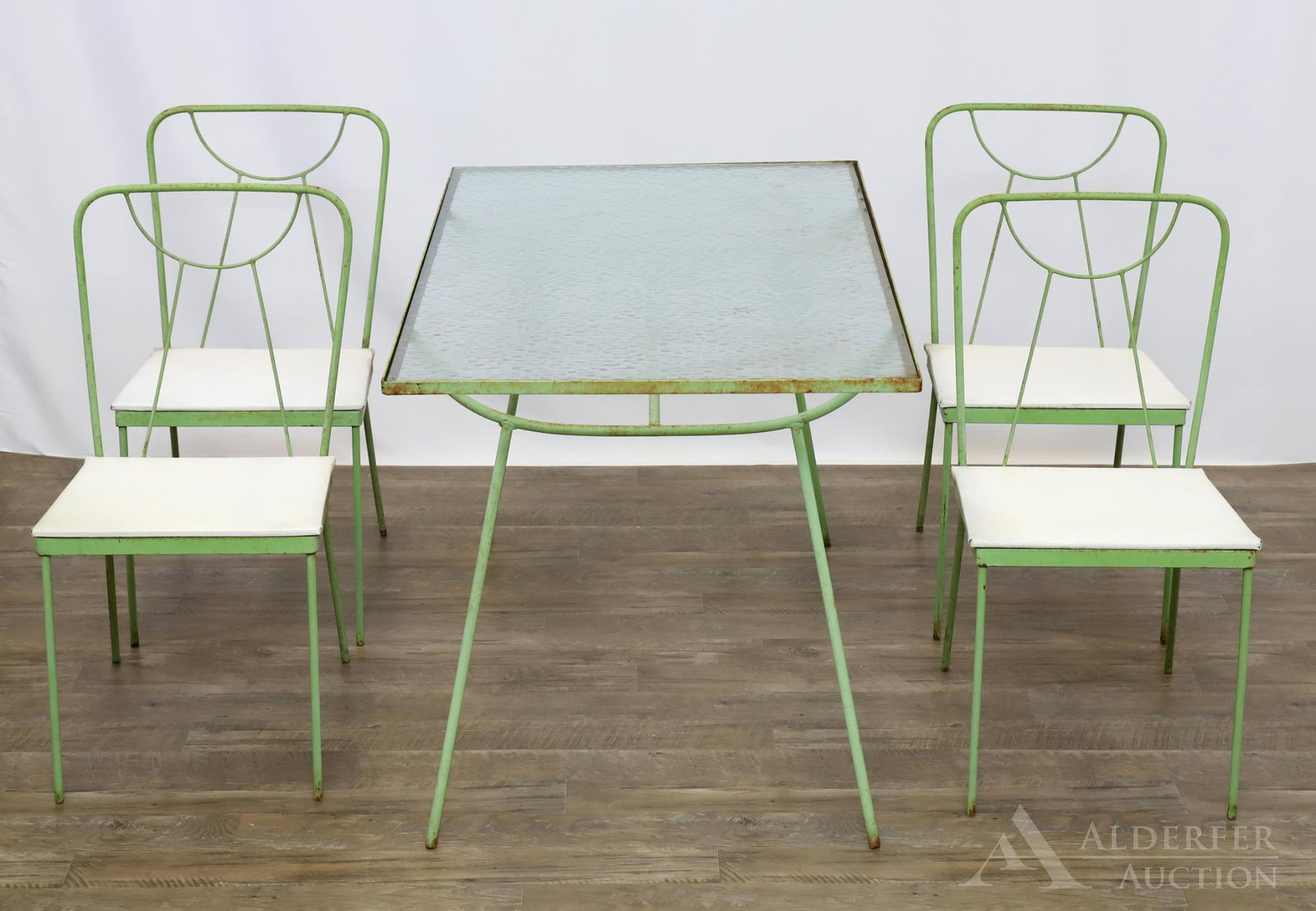 Wrought Iron Patio Set: Modernist wrought iron patio set in manner of George Nelson for Arbuck. Painted green wrought iron patio set includes (4) chairs and glass top table. 28.5"h x 49"w x 29"d (table) and 32.5"h x 16"w x 2