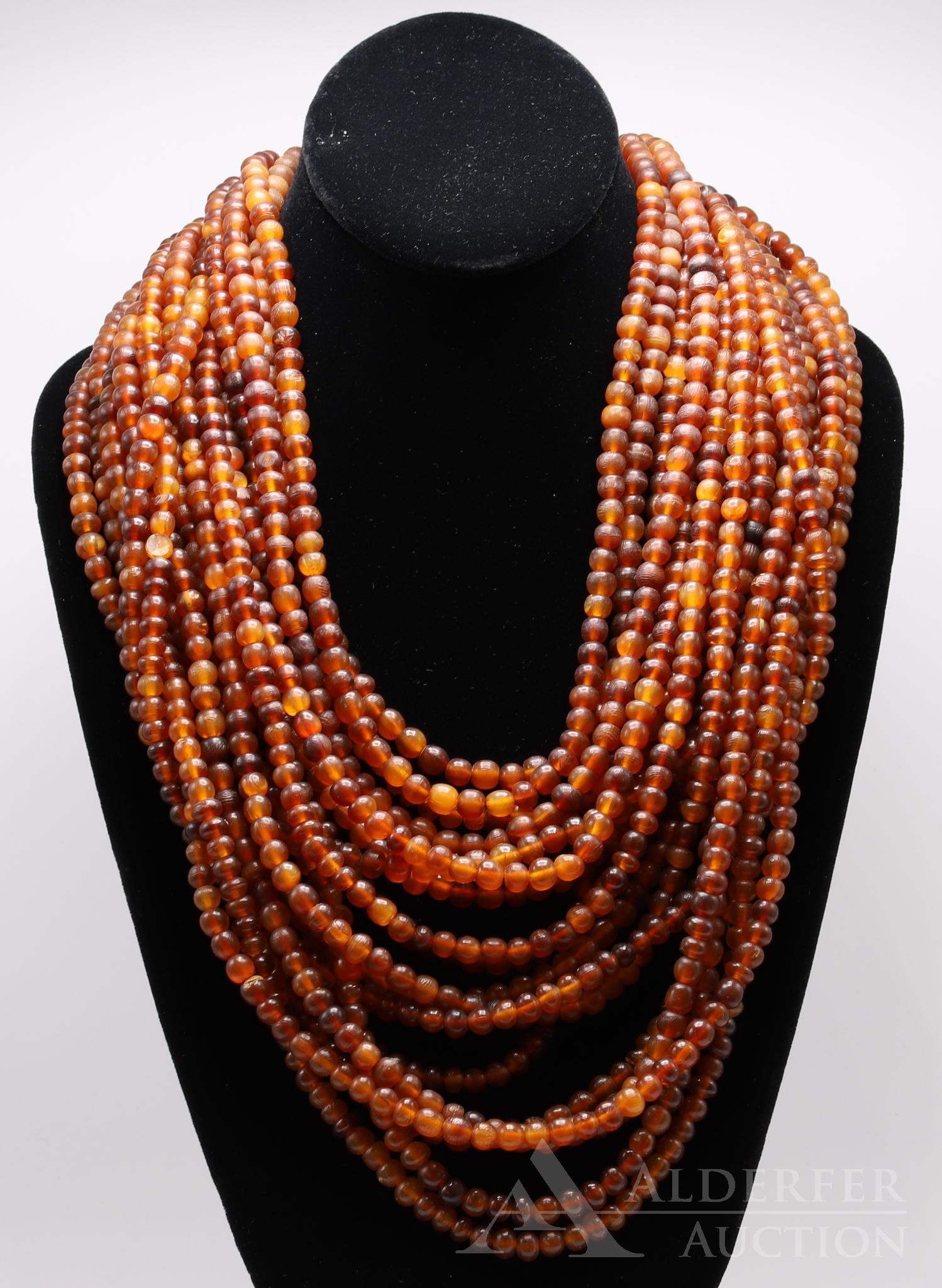 Lynggaard Monies Multi Strand Horn Necklace: GERDA LYNGGAARD POUR MONIES COPENHAGEN on round brass tag. 18 rows of natural amber brown horn beads with a horn closure. 21" long plus 3 1/2" drape.