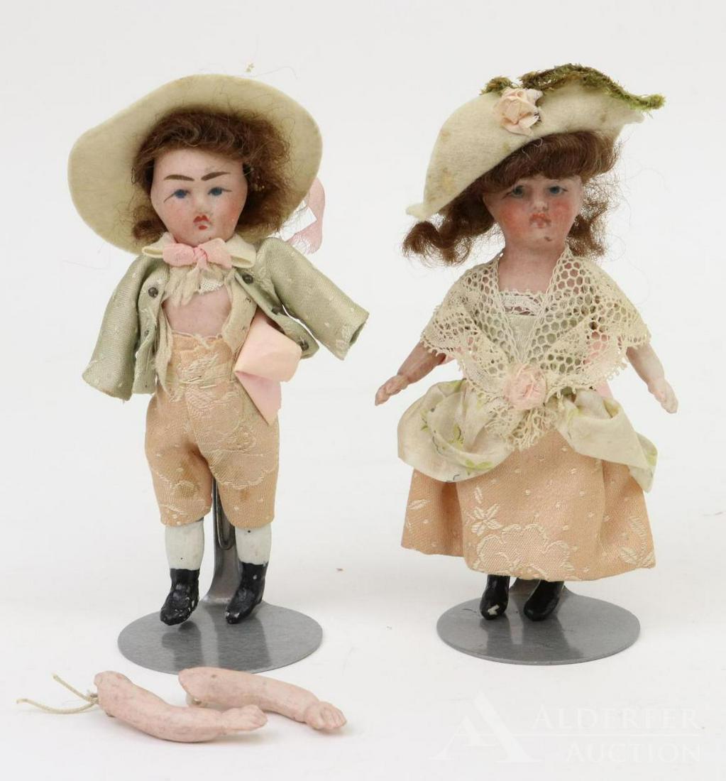 ANTIQUE FRENCH BISQUE HEAD DOLL(S).: Pair of 4 1/2" VERLIQUE all bisque boy and girl dolls. Painted features including blue eyes, closed mouths, brown mohair wigs. 5 Pc. bodies with painted black boots. Clothing appears to be factory ori