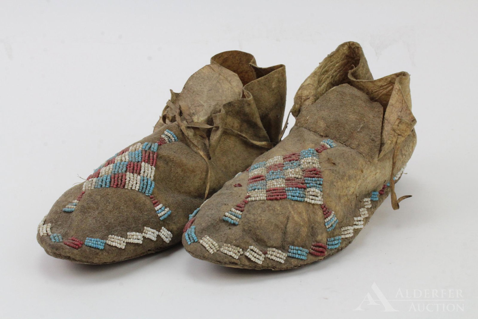 Pair Beaded Leather Moccasins: Cuffed hide moccasins with beaded red white and blue diamond design on front and 3-row block design on edges. 9" length