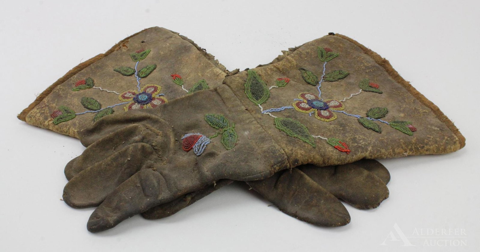 Pair of Native American Gauntlets: Leather gloves with beadwork of flowers and vines on front. Inside cuff marked "J Hayes". 13" length