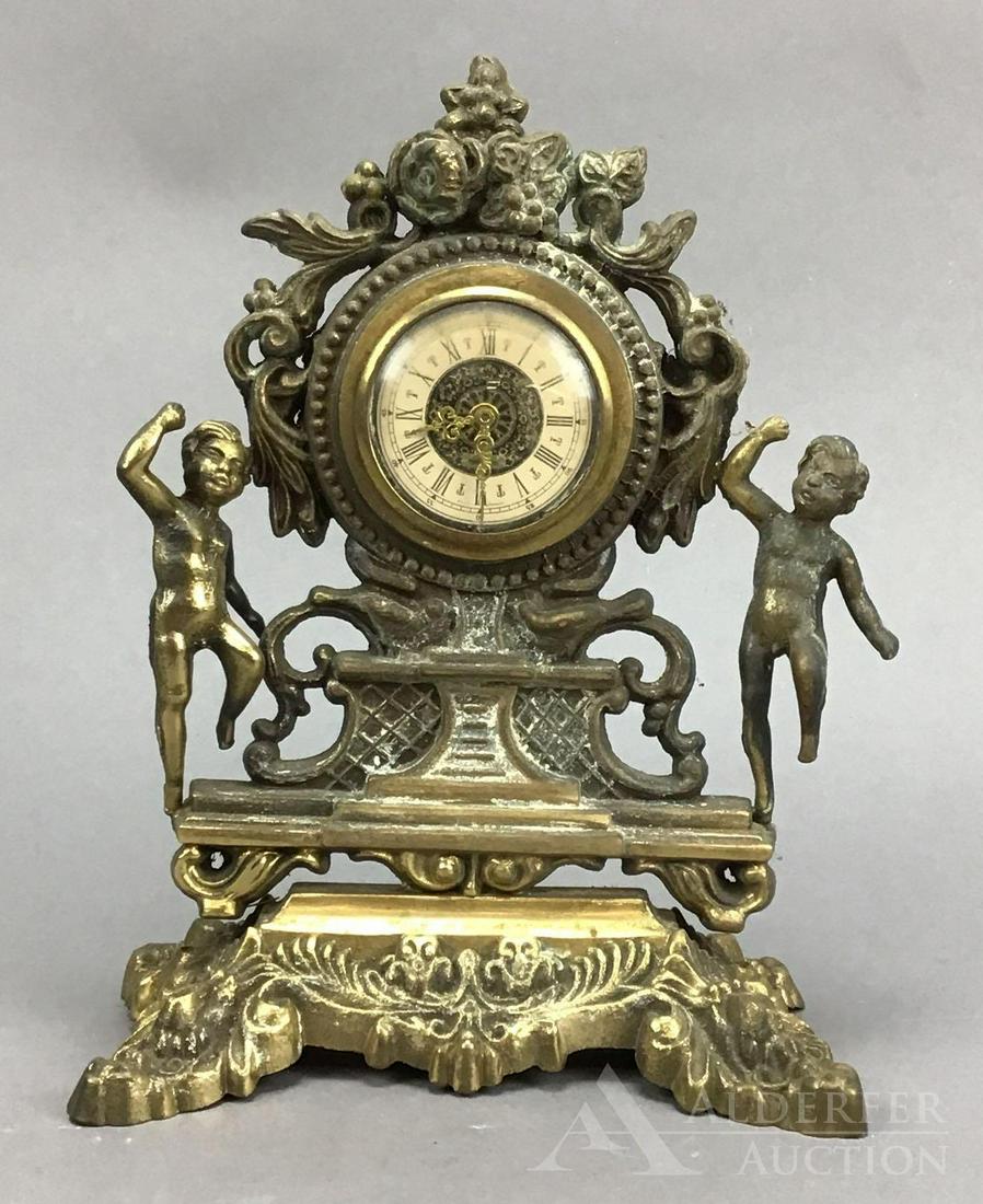 German Mantle Clock: Cast German mantle clock decorated with a pair of putti. 10”h x 7.25”w x 4”d