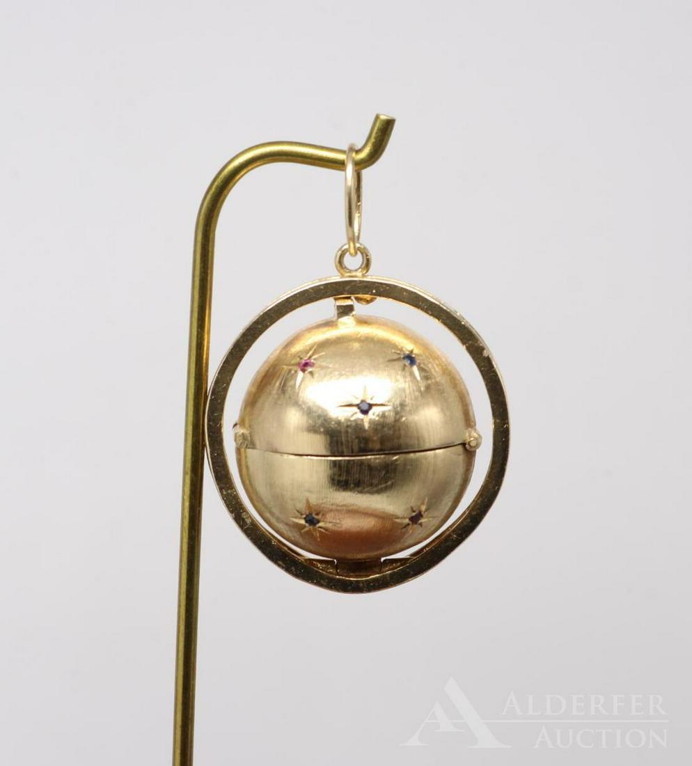 Gold Locket Pendant with Sapphire and Ruby: 14KY ball locket with small round Sapphires and Rubies in starbursts, opens to reveal a hinged folding triple circle frame. All closed up the sphere locks into place in the encircling 10KY gold fram