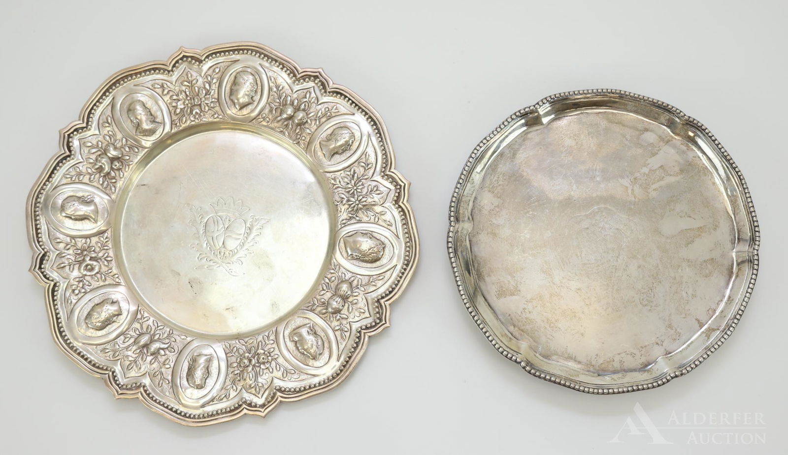 English Sterling Silver Tablewares: Grouping includes a Charles Stuart Harris tray dated 1894 London with Roman classical profiles on the border and a waiter set upon ball and claw feet dated 1897 London. Both decorated with armorial cr