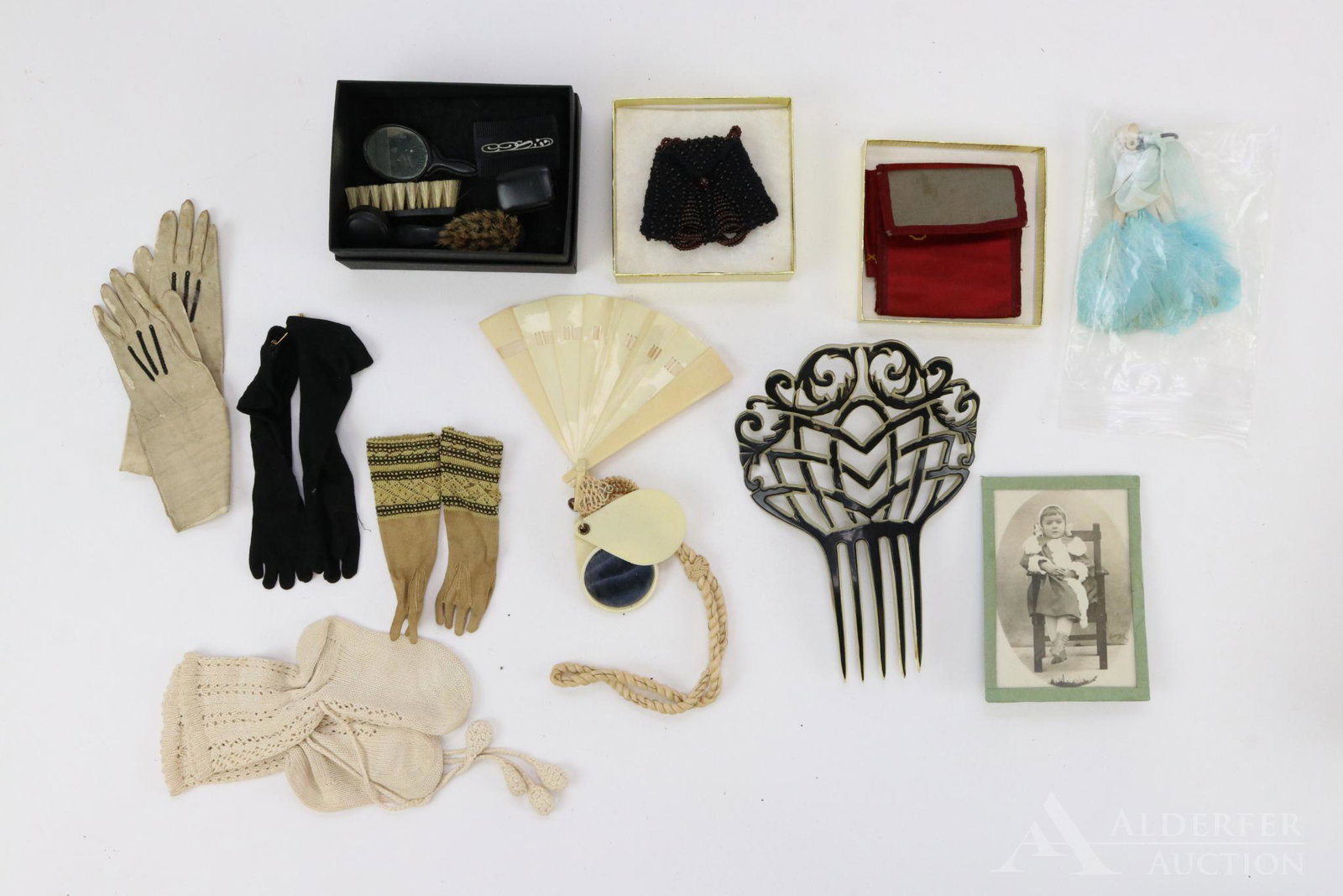 LOT OF ANTIQUE/VINTAGE ACCESSORIES.: Lot of antique doll accessories. (3) prs. of gloves: leather, cloth. Beaded purse. Celluloid fan and mirror on a cord to be worn on wrist. Pair of fancy baby booties. Bureau set with brushes comb, mir