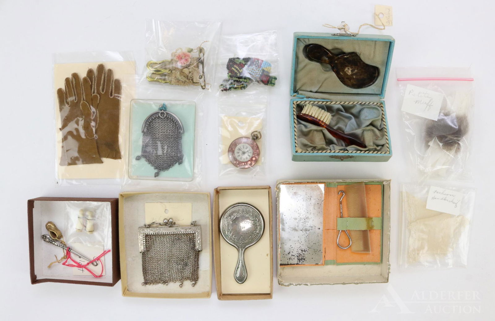 LOT OF ANTIQUE/VINTAGE ACCESSORIES.: Lot of antique doll accessories. Leather gloves. Sterling mesh bag 1.5ozt. Celluloid brush and hand mirror in little green trunk. Cases mirror, comb and button hook set. French Fashion handkerchief. A