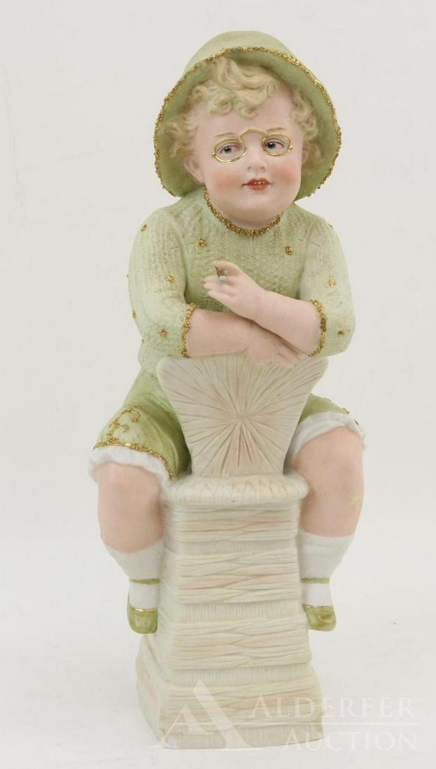 BISQUE FIGURINE LOT.: 14" Unmarked HEUBACH type. "Boy on Chair". Blue integlio eyes. Boy in pale green outfit with gold detail. Sitting backwards on a chair, he has a cigar in one hand. Condition: little finger broken on r