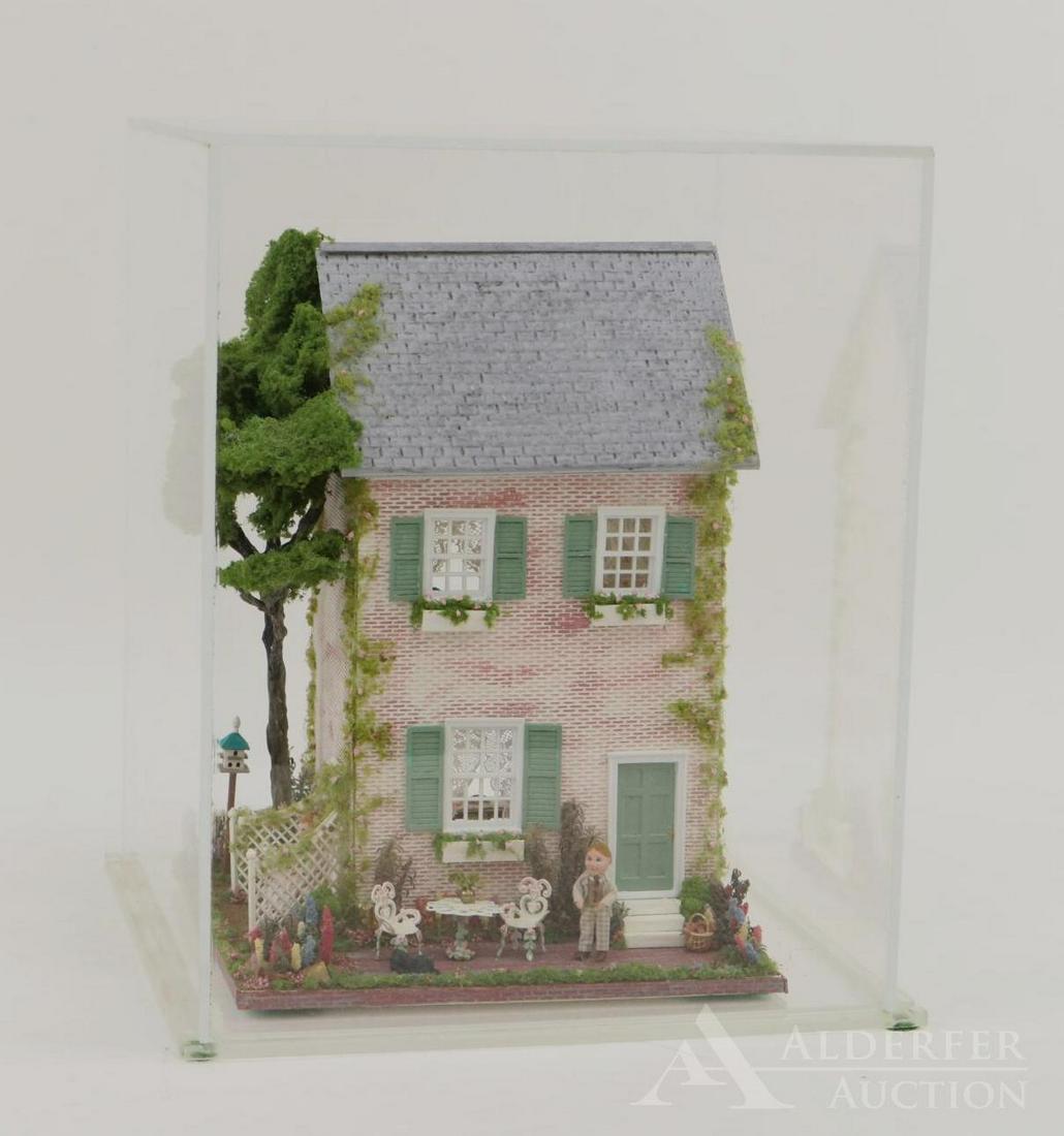 LOT OF MINIATURES IN DISPLAY CASE.: Plexiglass case - 10" T x 8" W x 8" D. Miniature cardboard "brick" colonial house is 8 1/2" T x 4 1/2" W x 4" D. Front of house has child and dog. Side of house has woman with baby in trellis like are