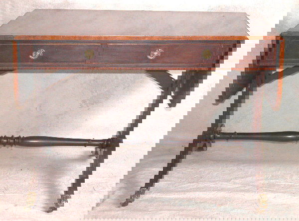 Duncan Phyfe Style Table.: Mahogany hall table with banded top and skirt, banded legs with brass tipped feet and castors, two drawers, cross stretcher base, 20th Century, 26"t., 60"l., 28 1/2"d. Condition: no defects observed.