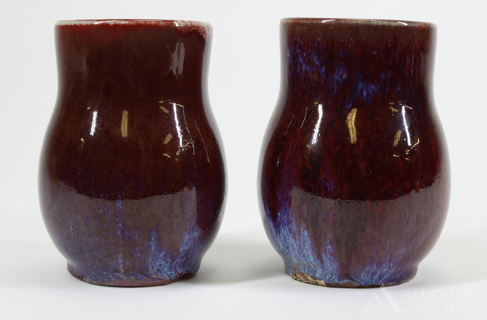 Qing Dynasty Sang de Boeuf Vases: Pair of Qing dynasty sang de bouef vases decorated in a rich flambe glaze with blue splash to the bases of both. 4.75"h