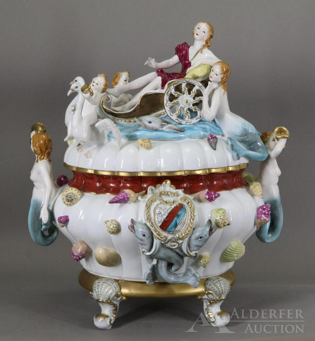 Meissen Porcelain Mermaid Tureen: Footed and reeded covered tureen decorated with mermaids, dolphins, putti, swans, lady in chariot, shells, and family crest, polychrome with gilt accents, marked. Repaired chip to the rim. 16.5”h x 