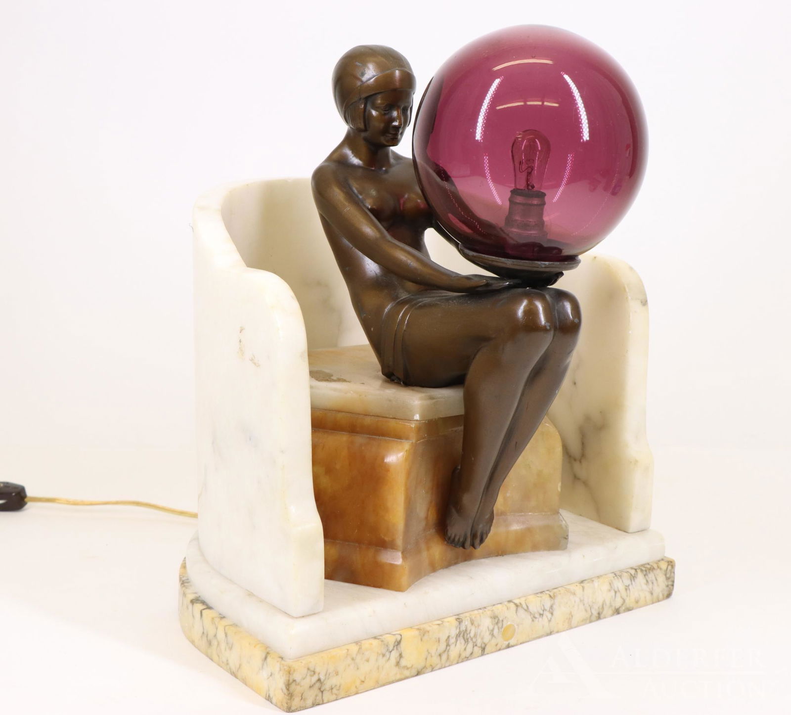 After Max Le Verrier (France 1891-1973) Sculptural Lamp: Art Deco figural lamp, "Delassement Lumineux", seated bronze finished white metal nude woman with marble surround, holding purple globe glass, unsigned. The globe and the base have lights. Turns on. 1