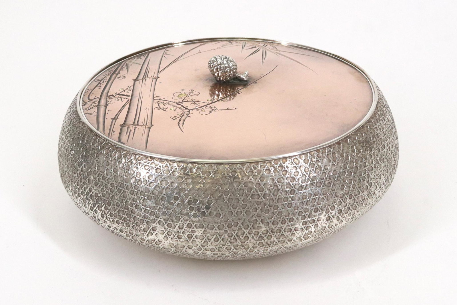 Kintaro Hattori Silver & Mixed Metal Box: Japanese Meiji era round silver box with basket weave motif, the cover is mixed metals in bronze and gold tones, with pinecone finial, engraved on both sides with bamboo and flower decoration, an