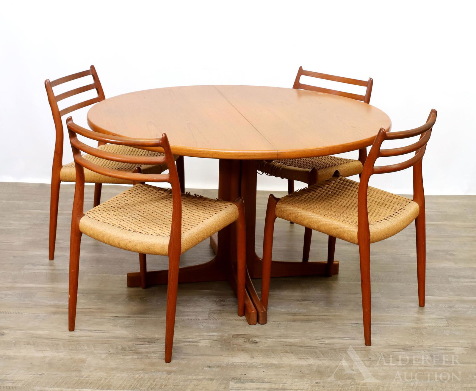J.L. Moller Danish Teak Dining Table and Chairs: One extension dining table with L-Shaped legs, 28.5"h x 46"round with two 24" leaves. Four side chairs with triple splats, woven seats, on tapered legs, 30"h x 19"w x 17"d, 17.5" seat height **Please