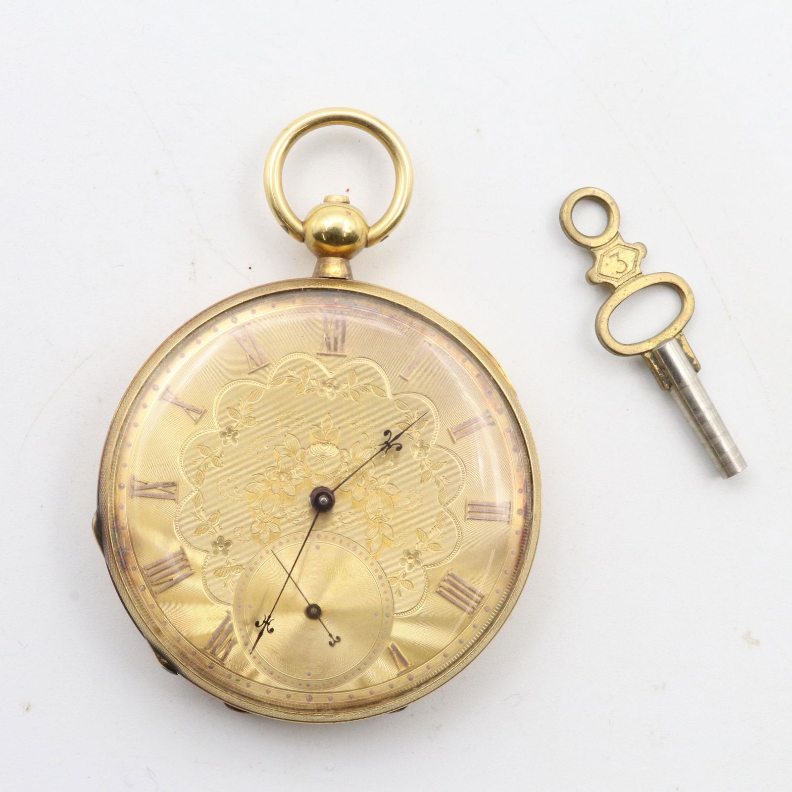 14KY Gold Pocket Watch: Engine turned and engraved open face case. Golden dial with floral design, Roman numerals and second subdial. Key wind/set, #3 key present, needs #7. Cuvette engraved "David J. Magnin Geneva N. 30527