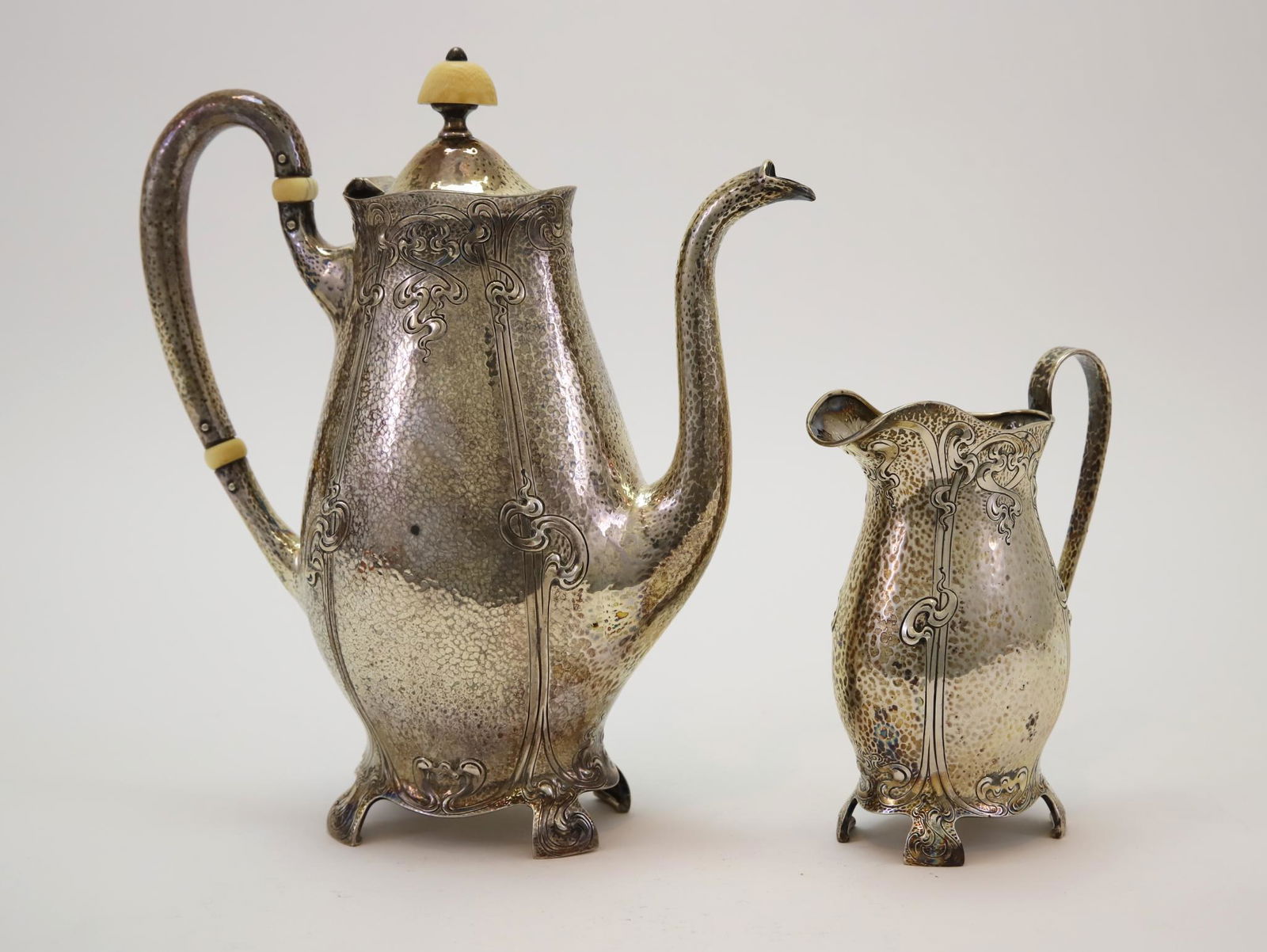 Barbour Sterling Silver Coffee Servers: Coffee pot and creamer with a hammered finish and Art Nouveau scroll decoration, retailed by Bagley & Co. Coffee pot 9"h x 7.75" from handle to spout. 23.20 ozt combined