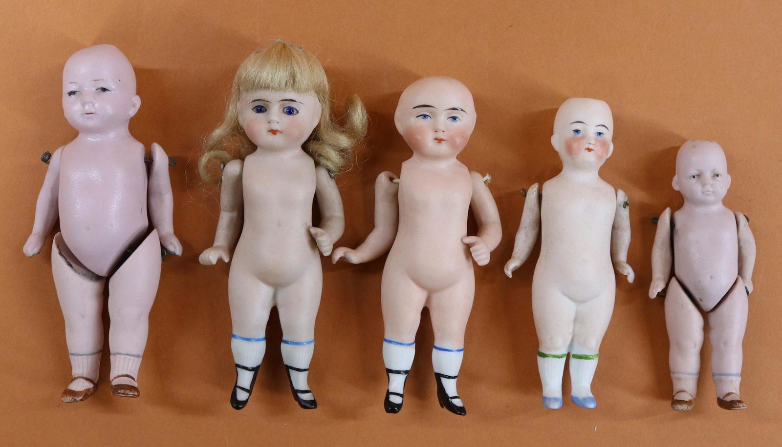 LOT OF ALL BISQUE DOLLS.: Lot of (5) German dolls that need wigs. 4" - 4 1/2". Pink bisque, wire strung, strung arms only. 620/9, 620/11, 8093 0 1/2. Solid dome unmarked (right thumb missing, needs restringing). Glass eye doll