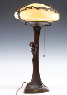 Art Nouveau Figural Table Lamp: Bronze base in the form of a woman standing next to a tree, with mushroom glass shade, with a plaque at the interior which bears the signature "Tiffany Studios, Broadway N.Y." Turns on. 23"h x 12"w