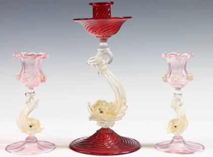 Murano Art Glass Dolphin Candlesticks: Italian blown glass candlesticks with gold aventurine dolphin stems, including a large example with ruby swirl base, drip pan, and nozzle, labeled at the foot, and a pair with pink tinted base and