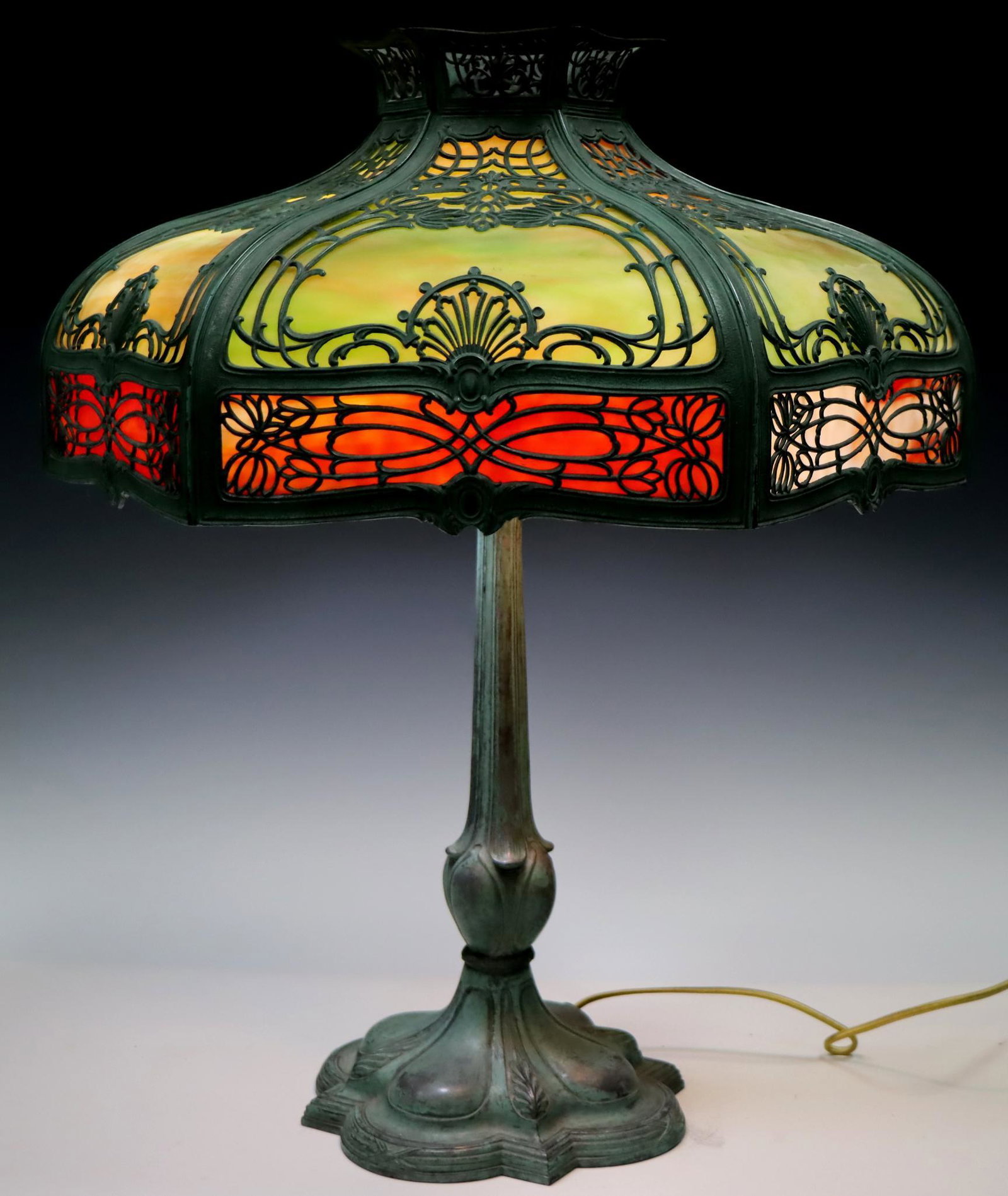 Slag Glass Lamp: Mottled green and red slag glass shade set in an art nouveau frame with brass base. 25"h x 20.5"w **Please Note: This item is NOT eligible for in-house shipping. Please refer to the terms and conditio