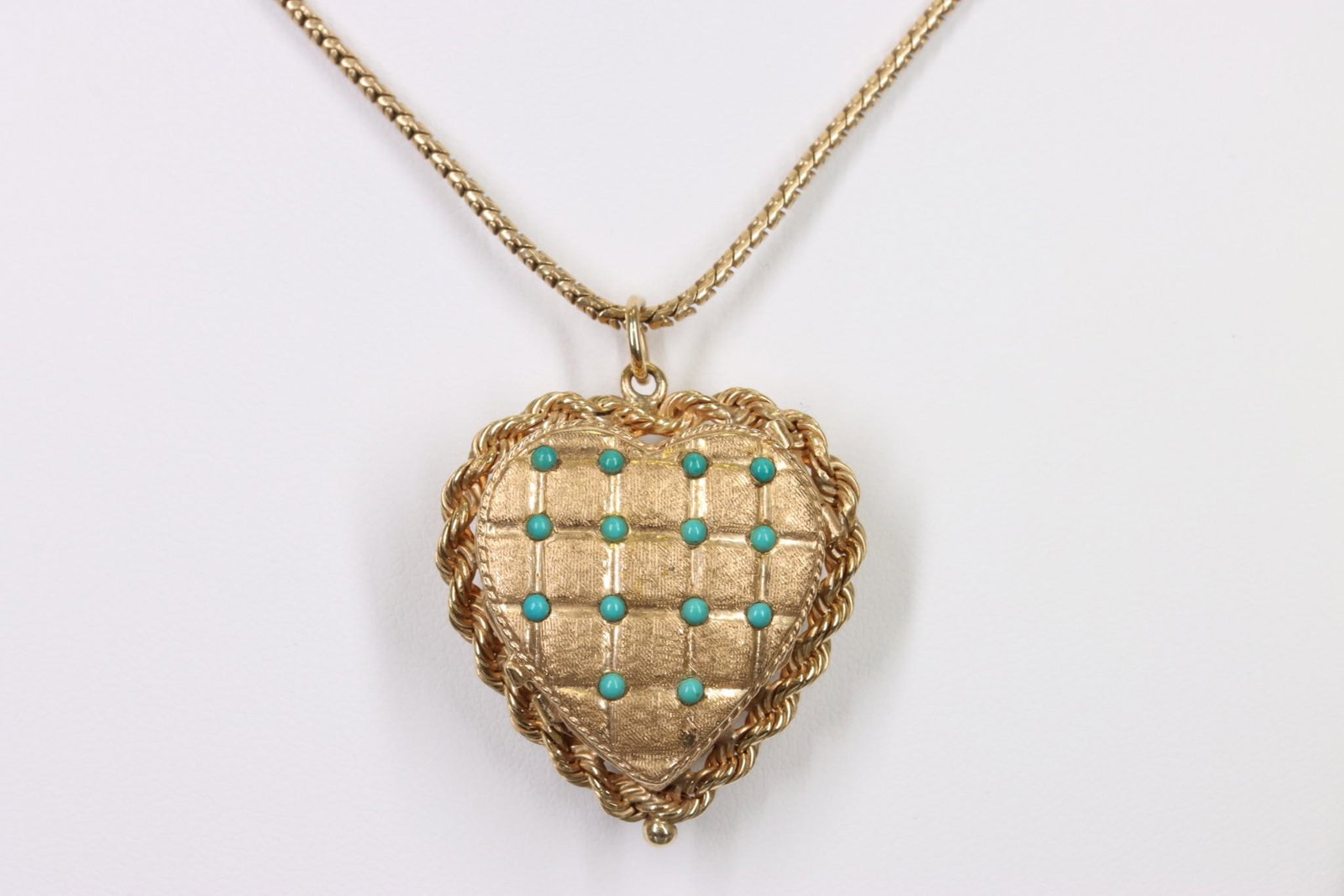 14K Gold Turquoise Heart Locket Pendant Chain: Heart locket pendant in 14ky gold features round turquoise cabochons on a quilted heart lid that opens to reveal an accordion of three heart frames stored in a heart box with rope perimeter. 1.25" hea