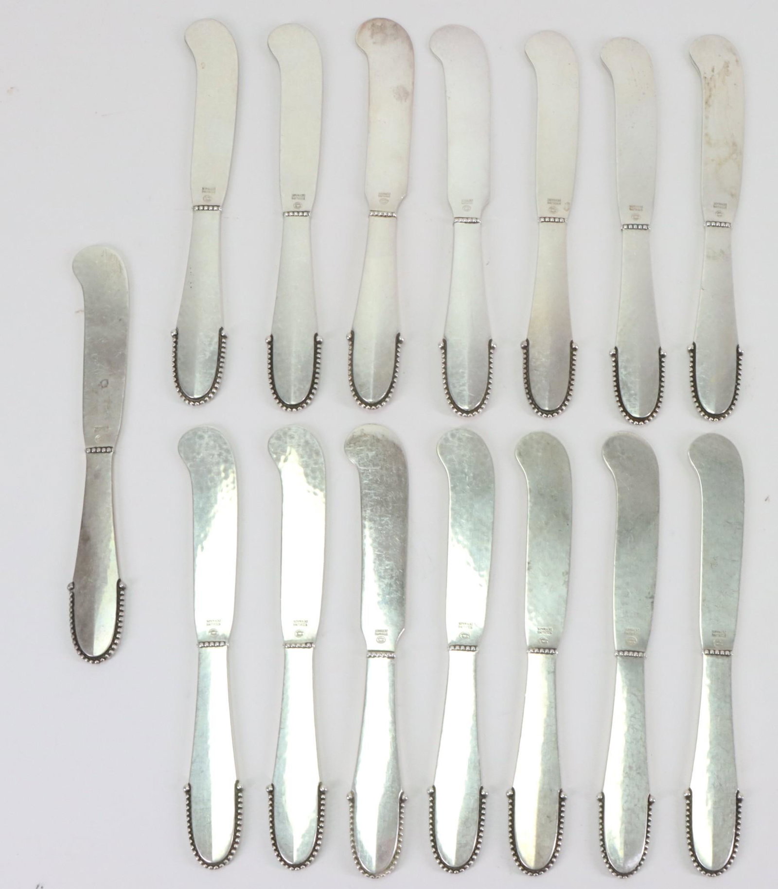 Georg Jensen "Beaded" Sterling Silver Butter Spreaders: Danish flatware with hammered finish, including (15) butter spreaders, 5.75", and 21.01 ozt.