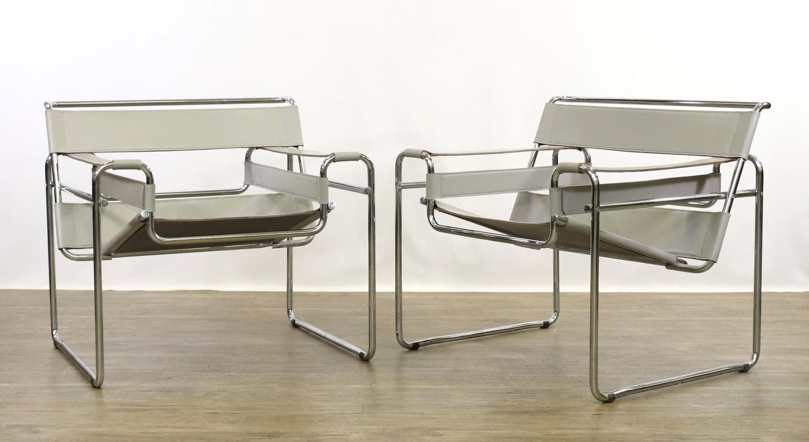 Marcel Breuer for Knoll Wassily Chairs: Pair of chairs having gray cowhide strap seats, arms, and backs on tubular steel chromed frames. Unmarked. 28"h x 31"w x 28"d, 17" seat height at the front **Please Note: This item is NOT eligible for