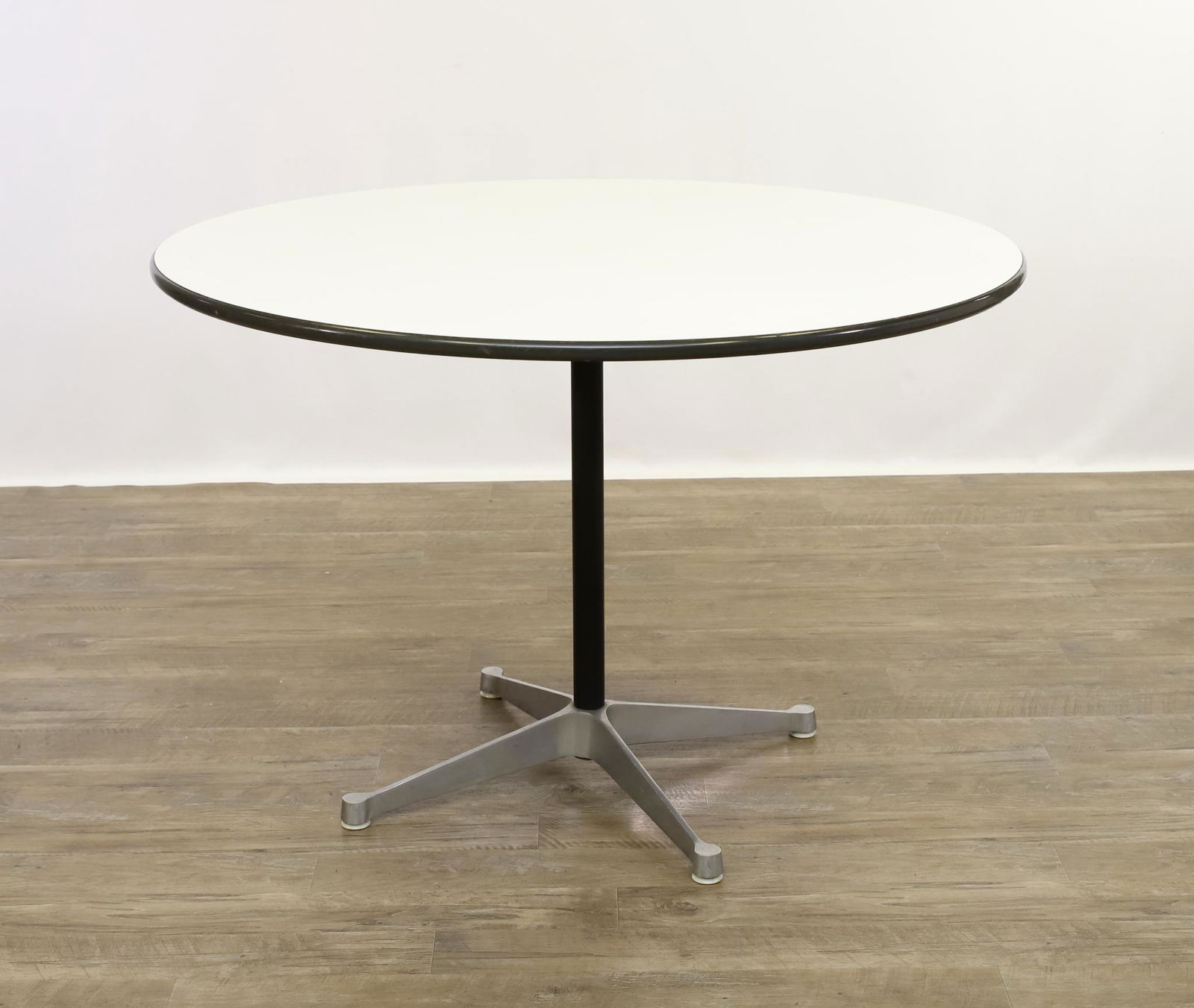 Charles Eames for Herman Miller Breakfast Table: White laminate top over a cast aluminum base with four legs. 29"h x 42"round **Please Note: This item is NOT eligible for in-house shipping. Please refer to the terms and conditions of this auction fo