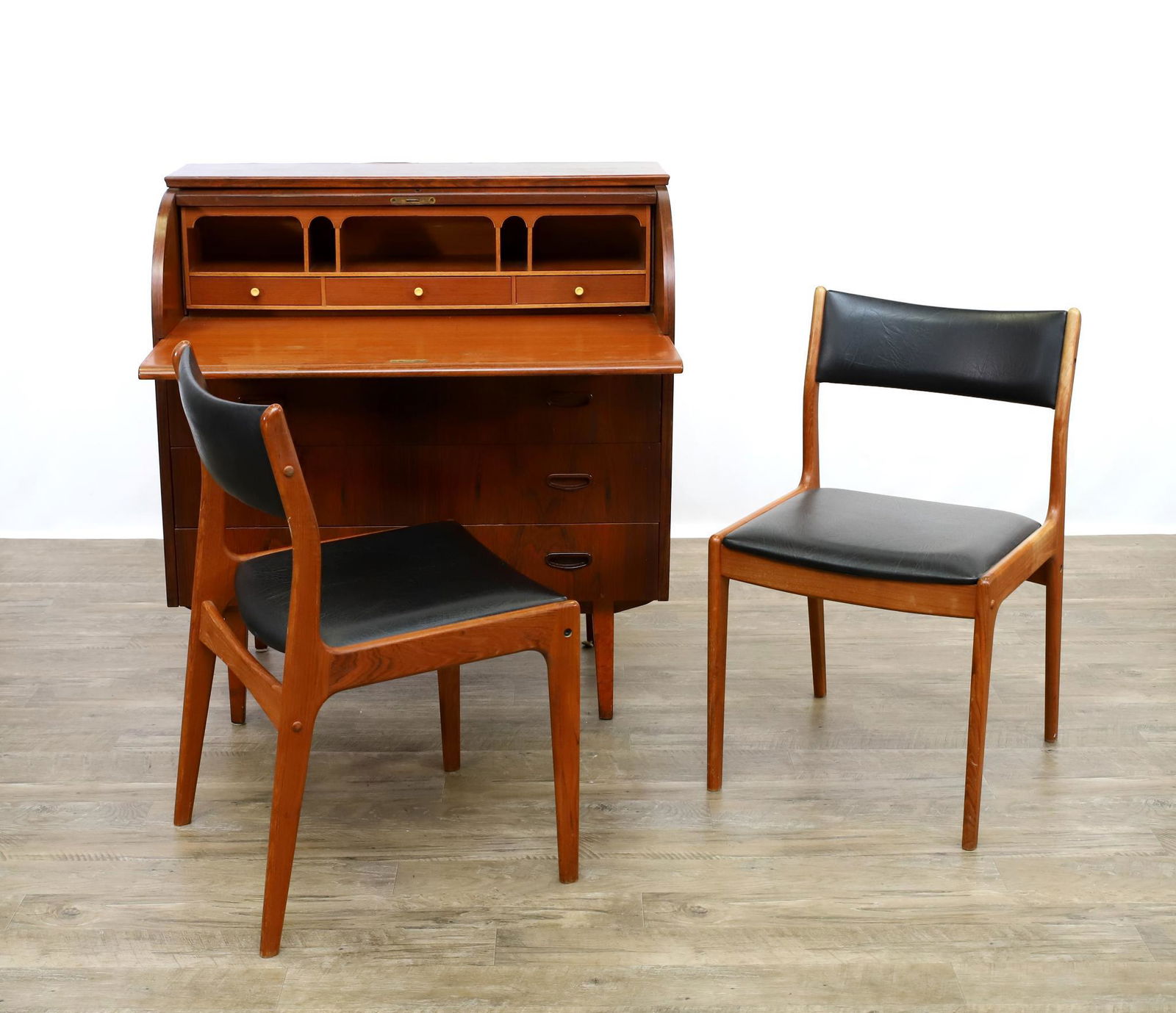 Danish Mid-Century Modern Desk and Chairs: Rosewood veneer cylinder desk with fitted interior, three drawers on tapered legs. Veneer loss to the back edge, 38"h x 35"w x 18"d. (2) Johannes Anderson teak side chairs with black vinyl backs and s