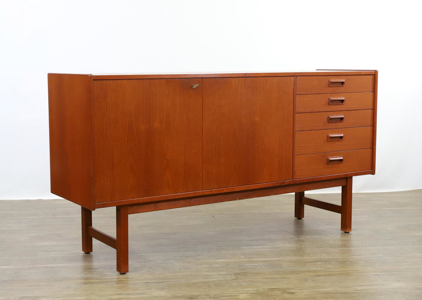 Danish Mid-Century Modern Teakwood Sideboard: Five graduated drawers with two doors on straight legs. 31.5"h x 60"w x 17"d **Please Note: This item is NOT eligible for in-house shipping. Please refer to the terms and conditions of this auction fo