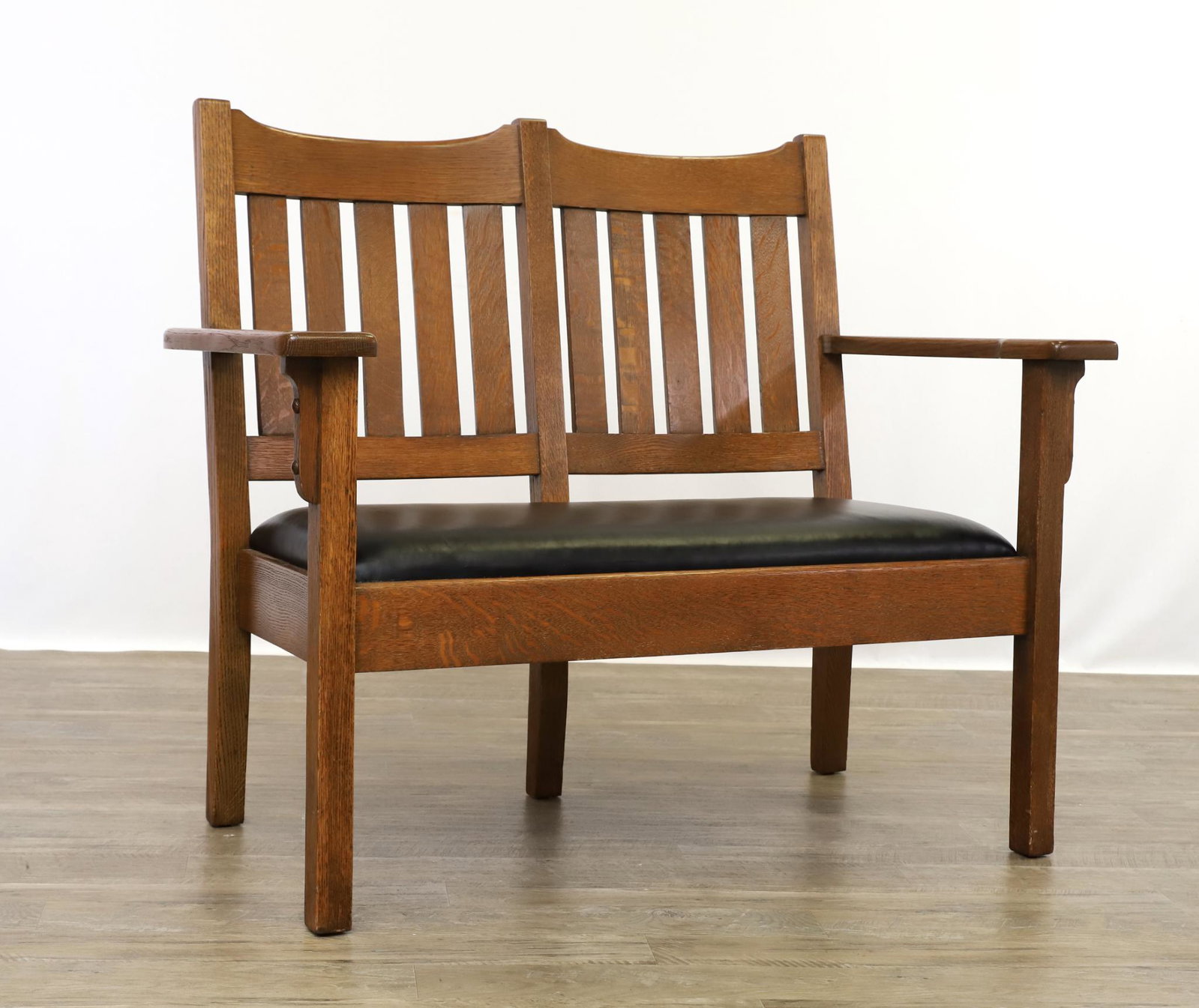 Arts and Crafts Settee Attributed to Stickley Brothers: Oak slat back settee with black vinyl seat, unmarked, early 20th c. 37.5"h x 45.5"w x 23.5"d, seat height 18" **Please Note: This item is NOT eligible for in-house shipping. Please refer to the terms 