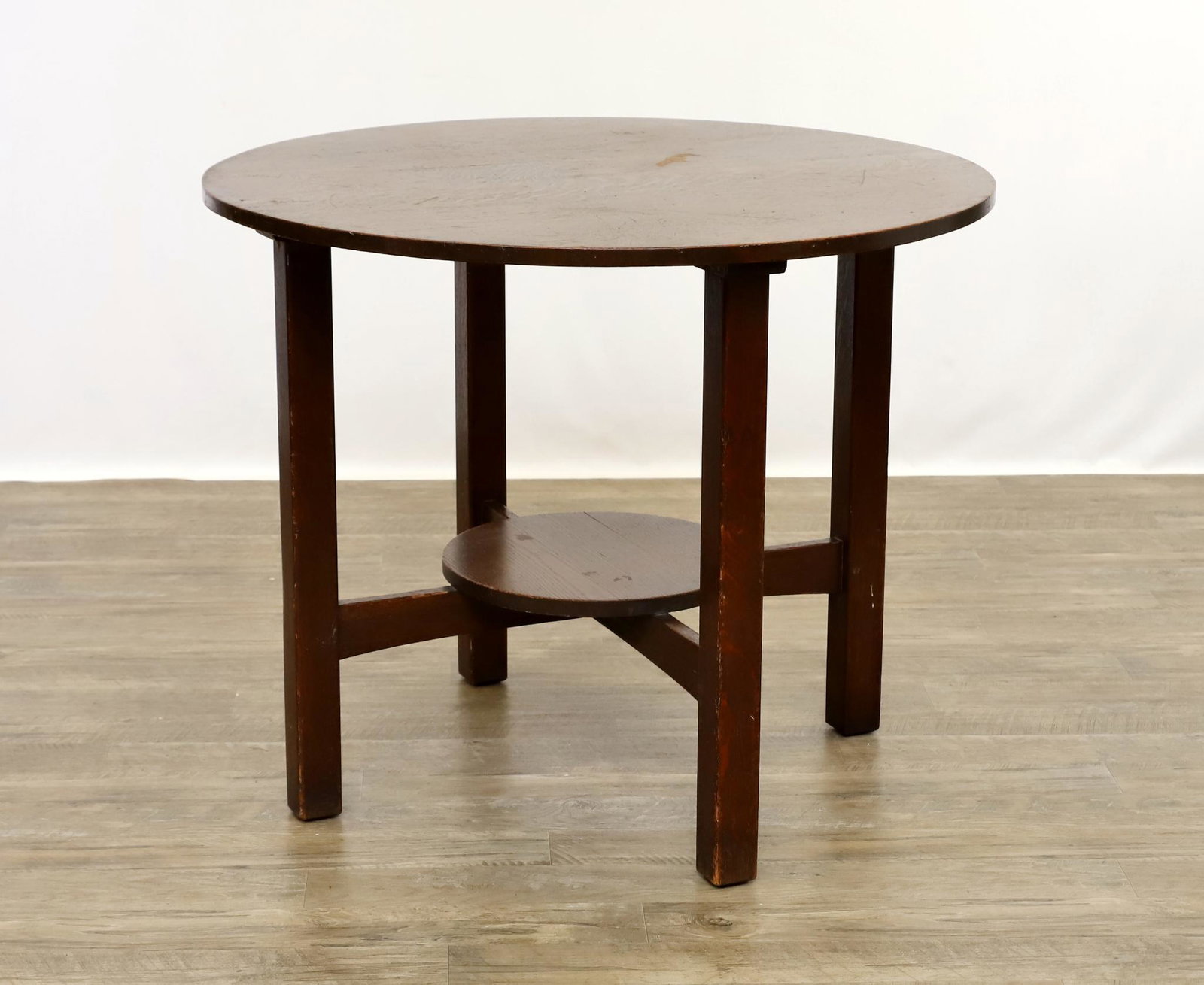 L. and J.G. Stickley Arts and Crafts Table: Quarter-sawn oak. Circular top with straight quadralinear legs and cross stretcher with lower tier, labeled, circa 1915. Surface wear and some shrinkage cracks to the top. Early 20th c. Table needs ne