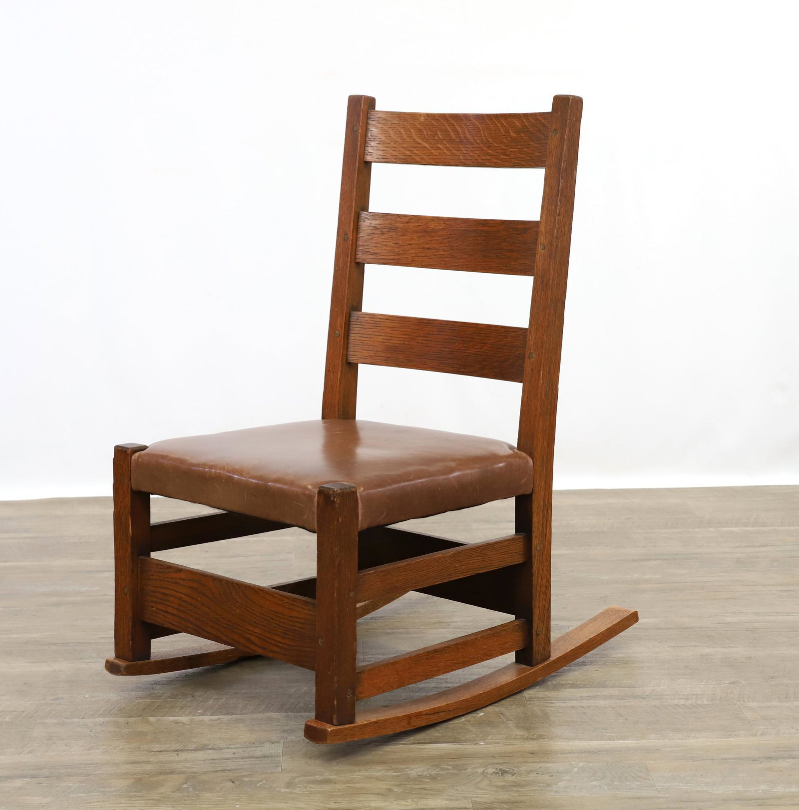 Gustav Stickley Arts and Crafts Sewing Rocker: Quarter-sawn oak ladderback rocking chair with peg construction leather seat, marked for Gustav Stickley, early 20th c. 31"h x 17"w x 25"d, seat height 13.5" **Please Note: This item is NOT eligible f