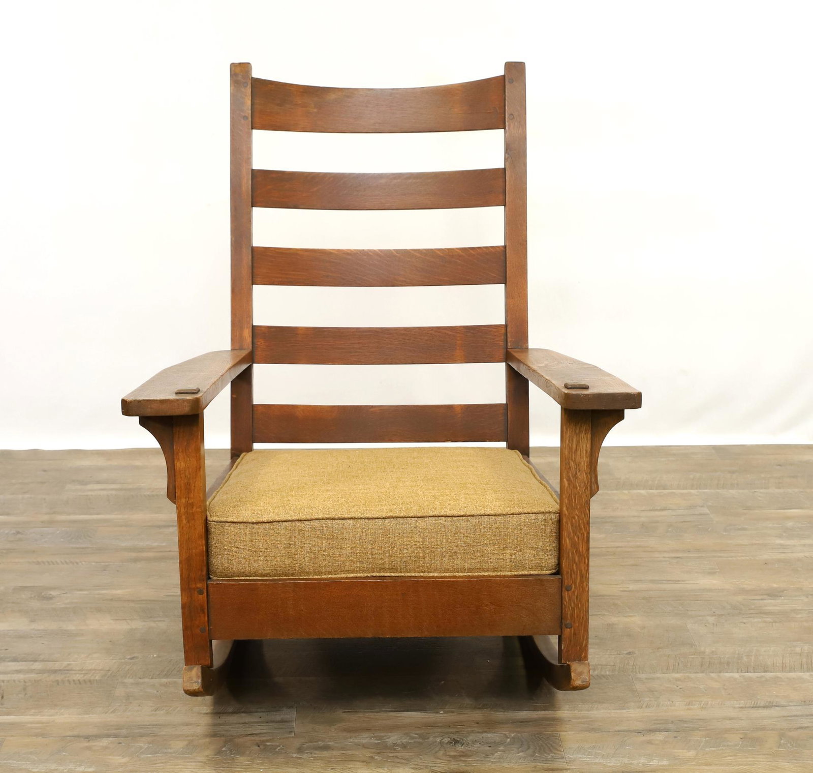 Arts and Crafts Rocker Attributed to Stickley Brothers: Quarter-sawn oak ladderback rocking chair with peg construction, quadralinear posts, corbel arm supports, slat seat and cushion, unmarked, early 20th c. 40"h x 31.5"w x 34"d **Please Note: This item i