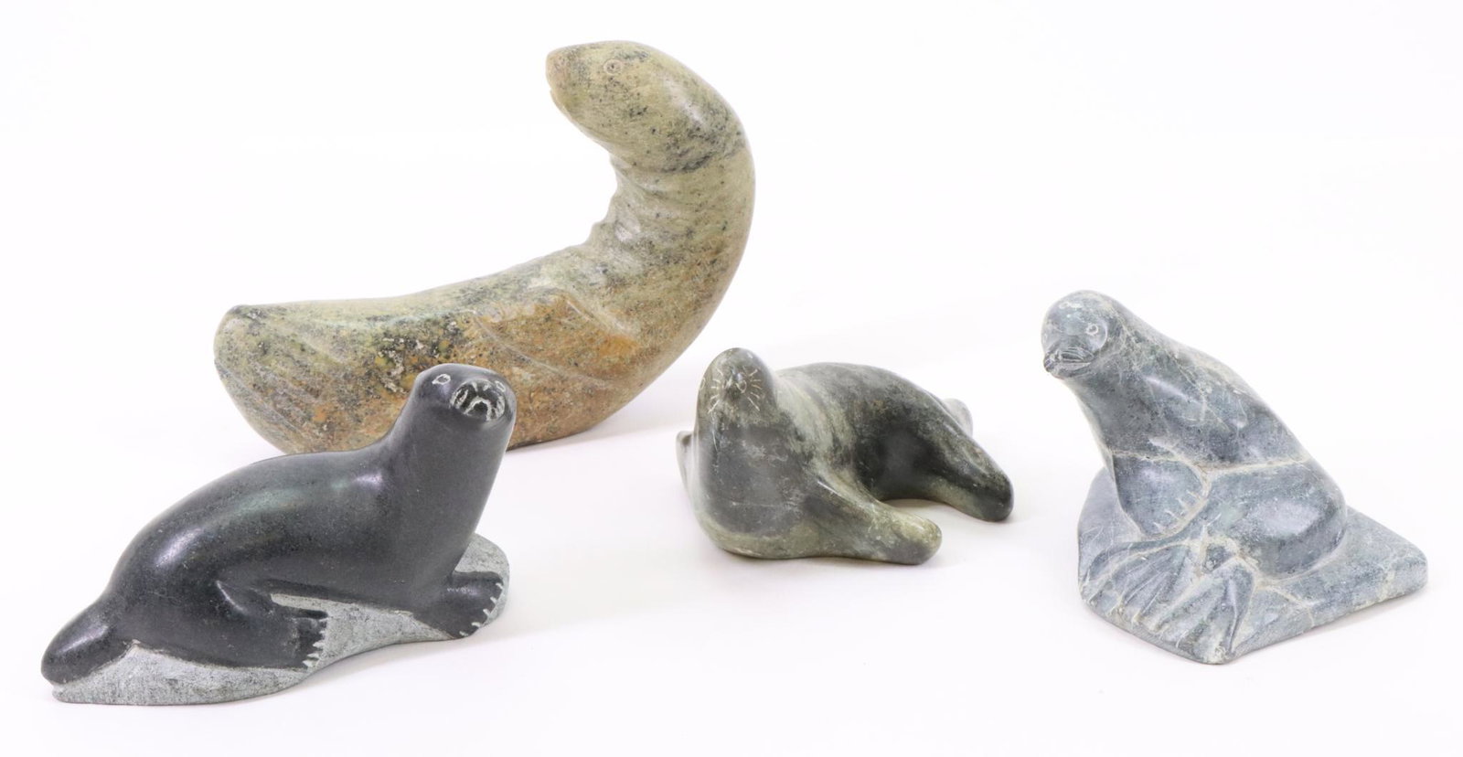 Inuit Carvings of Seals and Otters: Inuit carvings of an Otter with Canadian Eskimo Art label. Seal sitting on a rock with Canadian Eskimo Art label. Green seal signed "Owen" and green otter unsigned. Largest measures 4.5”h x 6.5&