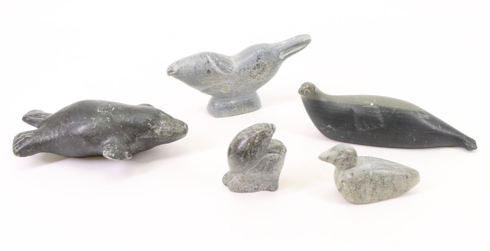 Inuit Carvings: Inuit carvings (5), all signed. Includes a swimming seals, seal on a rock, walrus and a duck. Largest measures 2.5”h x 5”w