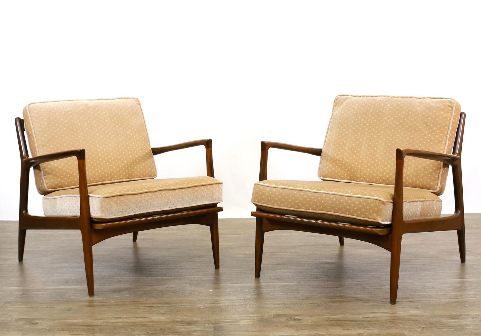 Ib Kofod-Larsen for Selig Lounge Chairs: Pair of teak slatback armchairs with straight rail, flared arms, tapered round legs, the back legs and stiles are joined, bowed and splayed, and the seat is supported with Fagas straps. Marked for Sel