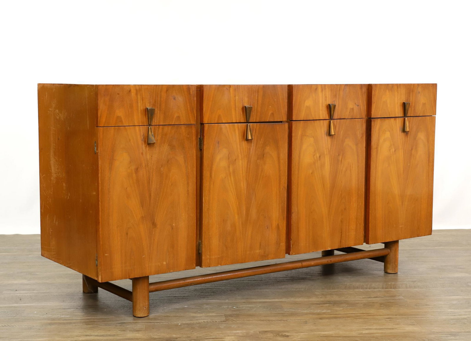 American of Martinsville Sideboard: Teak veneer with four drawers over four doors with fitted interior, butterfly pulls, on round straight feet and stretcher. Veneer loss. 31.5"h x 62"w x 19.5"d **Please Note: This item is NOT eligible 