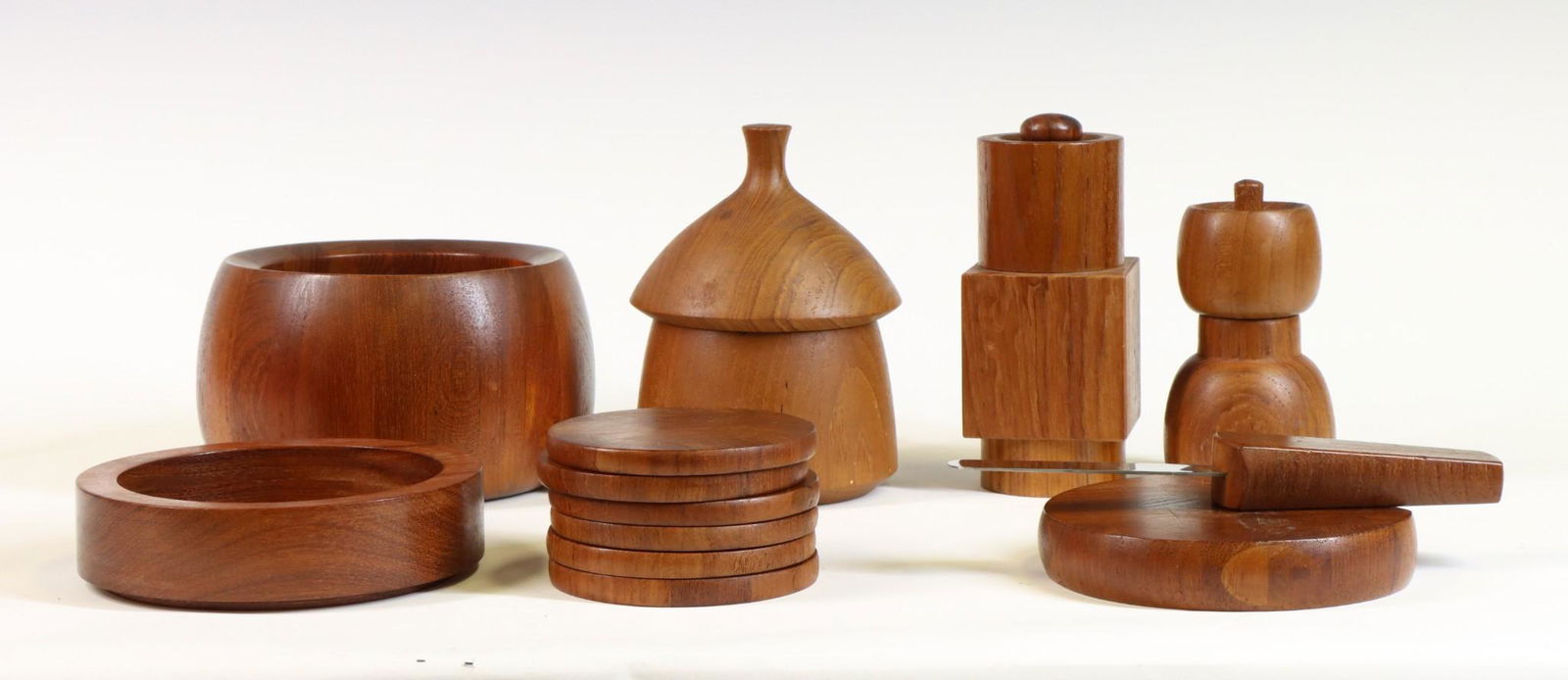 Dansk Tablewares by Jens Quistgaard: Tulip bowl, "Cylinder and Cube" and "Acorn" pepper mills, cheeseboard with fitted knife, and covered canister with glass insert, with unmarked wine bottle coaster and individual coasters (6). Tulip bo