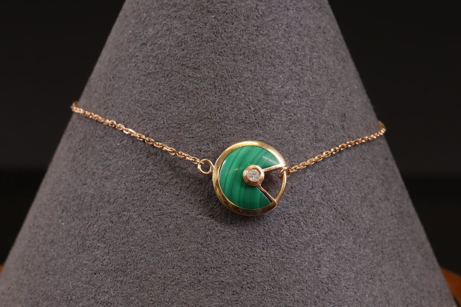 Amulette de Cartier Bracelet Malachite Diamond: Amulette de Cartier bracelet in 18k rose gold features a bezel set malachite semi-disk with a round diamond accent center. Chain is linked to a jump ring on one side of bezel and a ring slides along o
