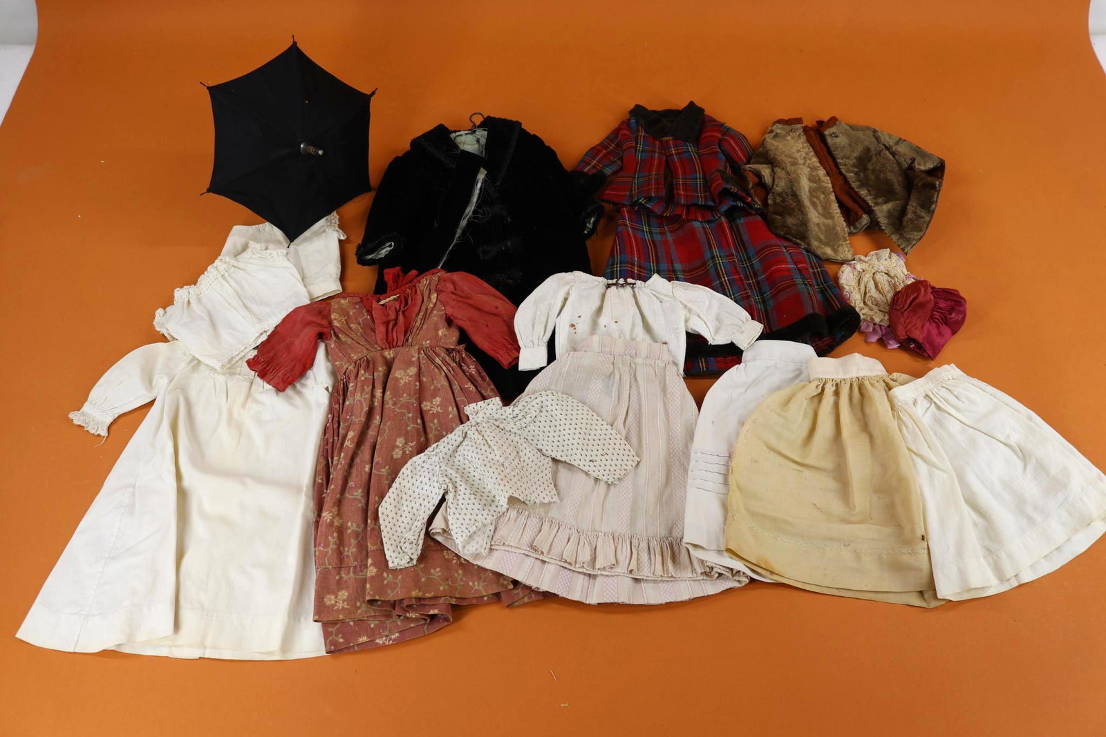 ANTIQUE DOLL/CHILDREN'S CLOTHING.: LOT of Doll clothing. Cotton - (3) Petticoats, (2) bodices, nightgown, blouse, stripe skirt, 12" print dress. 14" Black velveteen coat. 15" 2 Pc. wool plaid outfit. 8" Taupe fitted jacket. (2) Hats, b