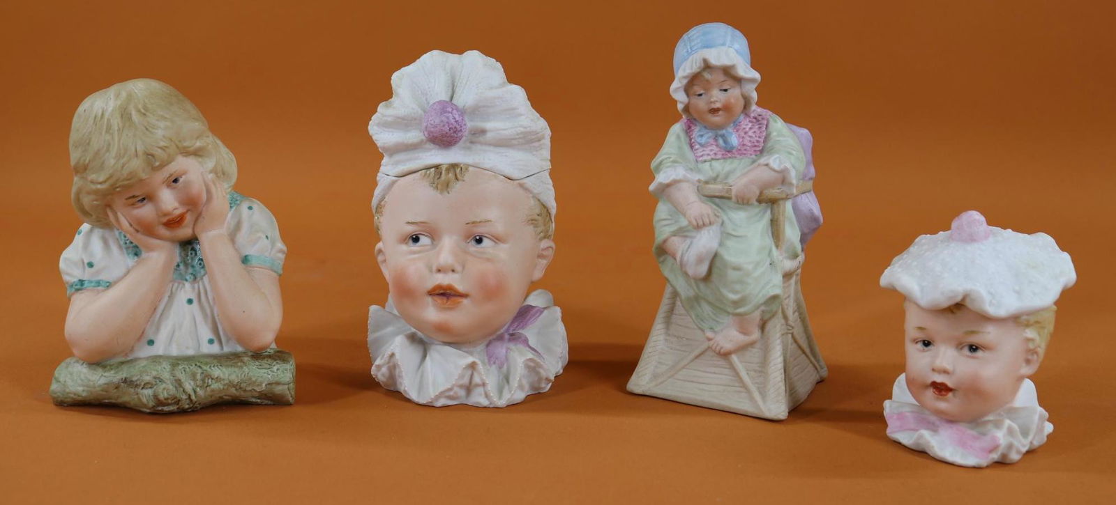 BISQUE FIGURINES.: Lot of (4) German items with intaglio eyes. Pair of figurines marked with the HEUBACH Sunburst. 5" Female child leaning on her elbows, from the waist up. Condition: nothing observed. 6 1/2" Baby sitti
