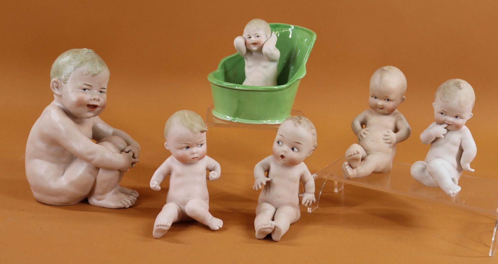 BISQUE FIGURINES.: Lot of (6) German items with intaglio eyes. All but (1) are clearly marked with the HEUBACH symbols. Lot of (4) "Action Babies". These are all approx. 5" T and are sitting down. They have the HEUBACH