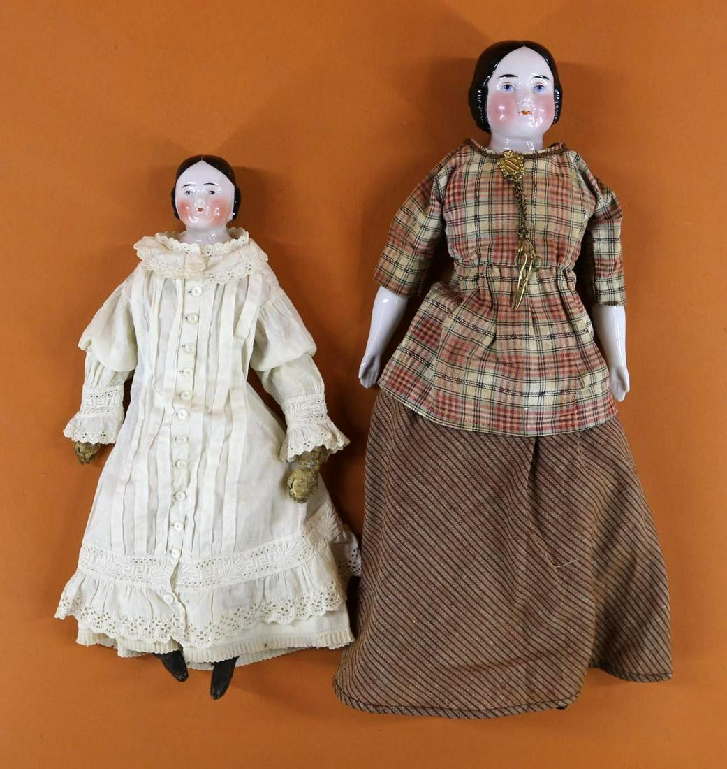 CHINA HEAD DOLL(S).: Pair of antique dolls with black 1865 style center part hair, high forehead. Both are wearing antique cotton clothing. 12" Doll has BROWN eyes, rosey cheeks. Vintage cloth body, white leather lower ar