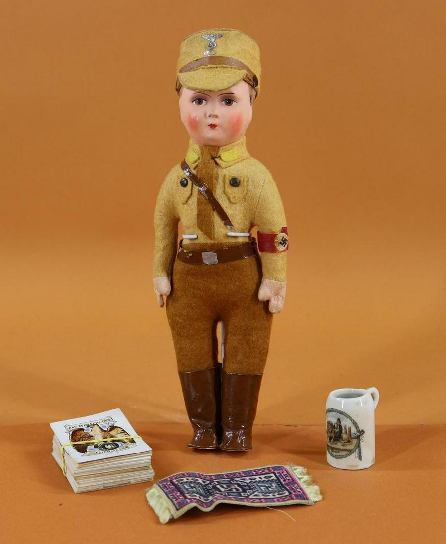 MILITARY DOLL(S).: LOT. 10 1/2" GERMAN pressed cardboard "Hitler Youth" doll. Cloth body with felt clothing, arm band, oilcloth boots. Comes with china stein, flannel cigarette rug. Also - group of small booklets dated 