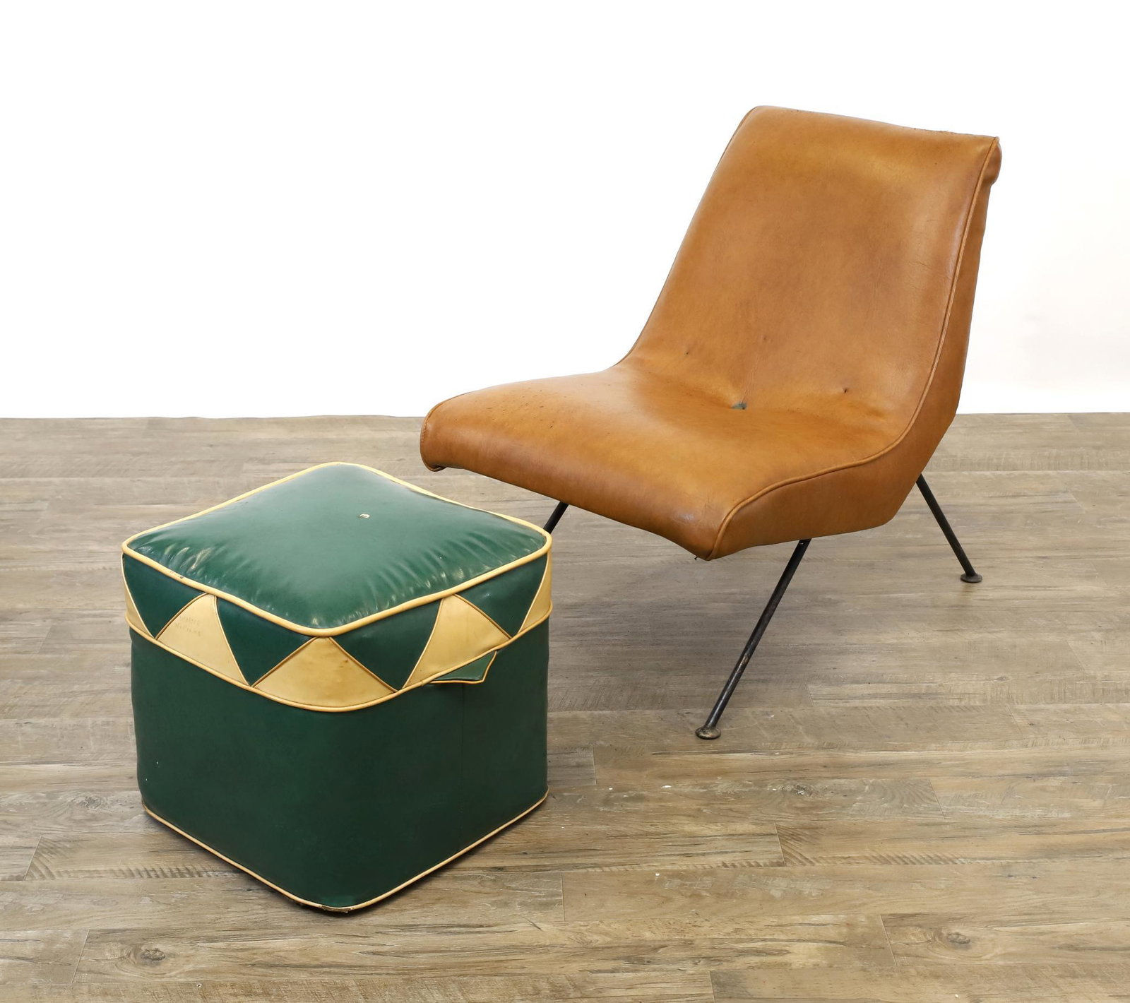 Mid-Century Modern Scoop Chair and Pouf: Tan vinyl scoop chair on iron frame with splayed legs, 28"h x 21"w x 26"d, seat height 15.5". Green and white vinyl pouf foot stool, 15"h x 15"w x 15"d. Wear to the upholstery including stains, scuffs